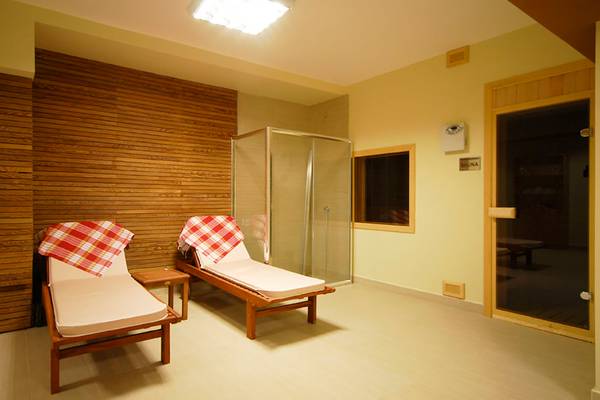 Saunaraum im Meril Hotel mit zwei Liegen und einem Glastür-Eingang zur Sauna.