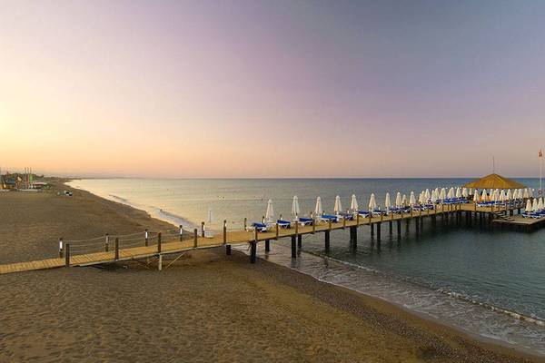 Blick auf die Pier des Blue Waters Club am Strand bei Sonnenuntergang.