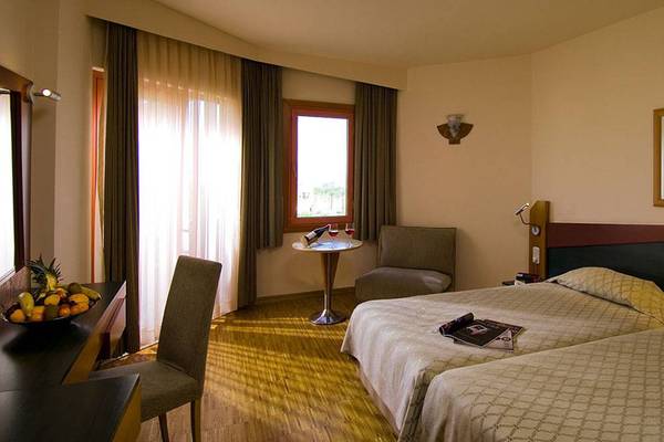 Doppelzimmer im Blue Waters Club Hotel mit zwei Betten, Tisch und Fenstern.