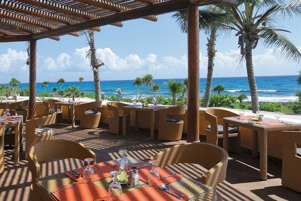 Außenterrasse des Barcelo Maya Palace Hotels mit Blick auf den Ozean und Palmen