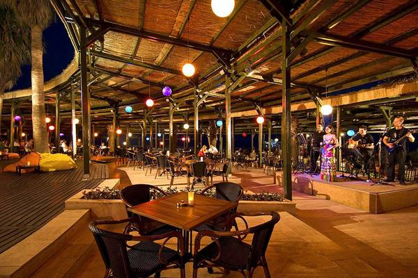 Blue Waters Club Außenbereich mit Bühne, Musikern und Gästen bei Nacht.