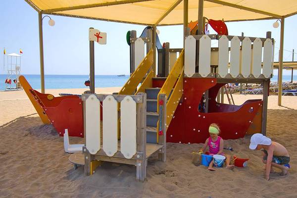 Kinder spielen am Sandkasten und Spielturm am Strand im Blue Waters Club Hotel.