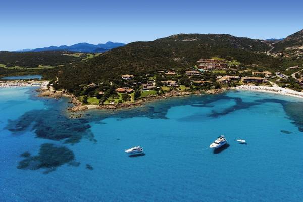 Luftaufnahme des CPH Pevero Hotels auf einer Insel mit kristallklarem Wasser und Yachten.