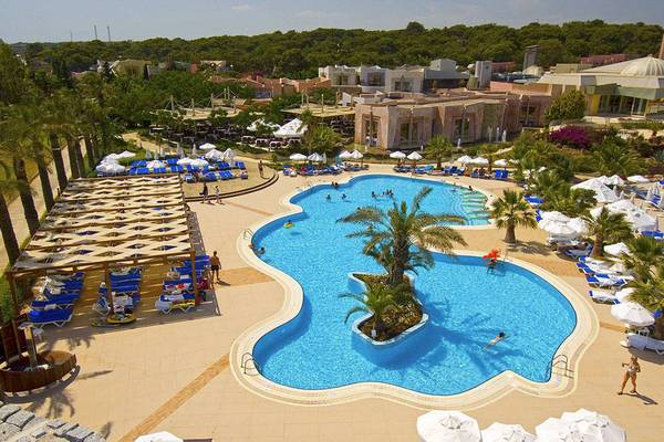 Luftaufnahme des Blue Waters Club Resorts mit Außenpool, Sonnenliegen und weißen Sonnenschirmen.