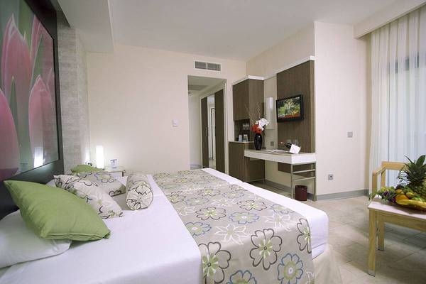 Schlafzimmer im Blue Waters Club Hotel mit Doppelbett, Fernseher und Obsttablett.