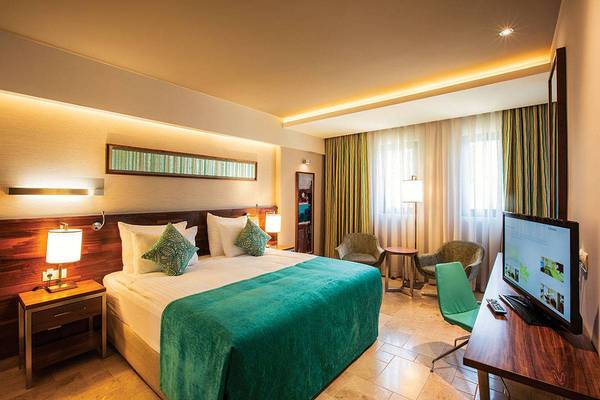 Luxuriöses Zimmer im Blue Waters Club Hotel mit grüner Bettdecke und modernen Möbeln.