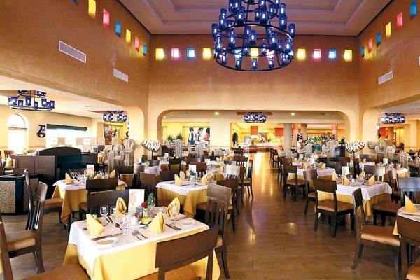 Restaurant des Barcelo Maya Palace Hotels mit vielen gedeckten Tischen und bunten Kronleuchtern.