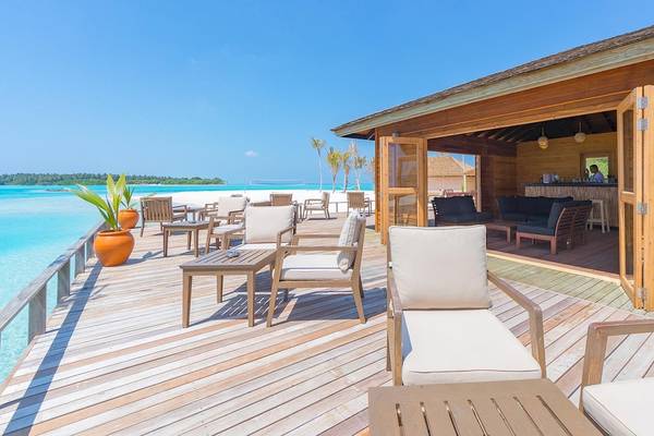 Außenbereich des Innahura Maldives Resorts mit Blick auf das Meer und weißen Stühlen.