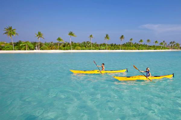 Zwei Personen auf gelben Kajaks im kristallklaren Wasser vor der Insel Innahura, Maldives Resort.