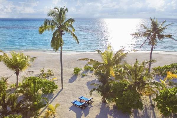 Strand des Innahura Maldives Resort mit Liegen und Palmen im Schatten