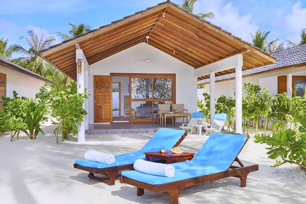 Außenbereich der Innahura Maldives Resort Villa mit zwei blauen Liegen und einem Tisch auf einem sandigen Strand.