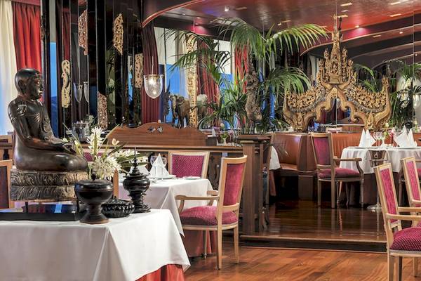 Innenansicht des Botanico & The Oriental Spa Garden Hotels mit Buddha-Statue, Pflanzen und gedeckten Tischen.