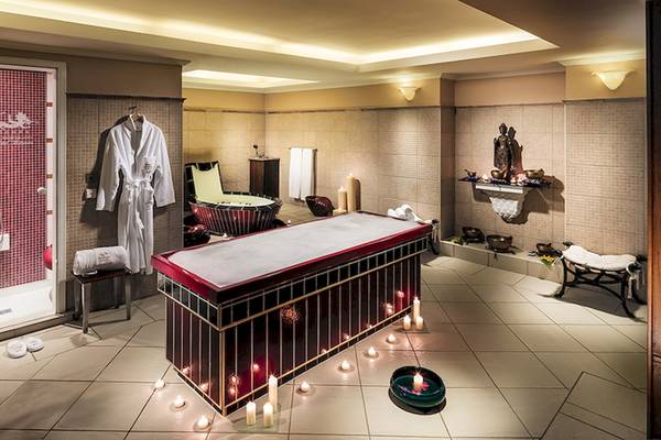 Behandlungsraum im Botanico & The Oriental Spa Garden Hotel mit Massagetisch, Kerzen und roten Fliesen.