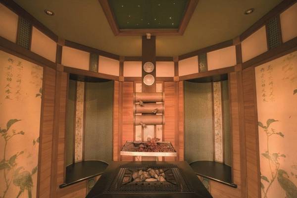 Innenansicht der Botanico & The Oriental Spa Garden Sauna mit Holzwänden, grüner Decke und Steinen.