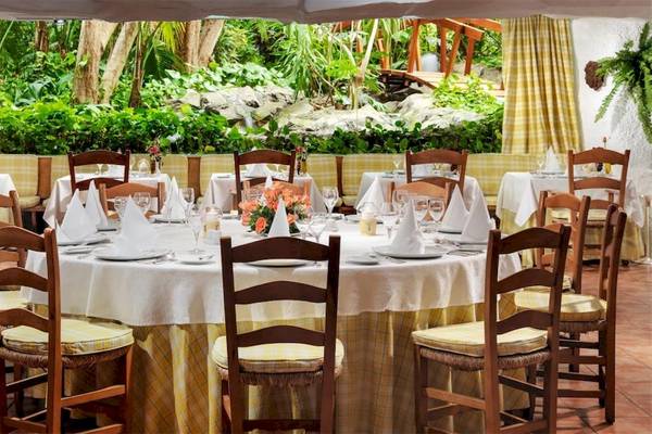 Ein Restauranttisch im Gartenbereich des Botanico & The Oriental Spa Garden Hotels mit gelben und weißen Tischdecken und Tischkarten.