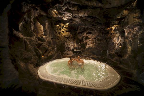Paar in einem Schwimmbad in einer Höhle mit einer Buddha-Statue im Hintergrund
