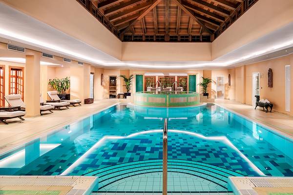 Ein großer Swimmingpool mit einer grünen Umrandung und Lounge-Stühlen im Botanico & The Oriental Spa Garden.