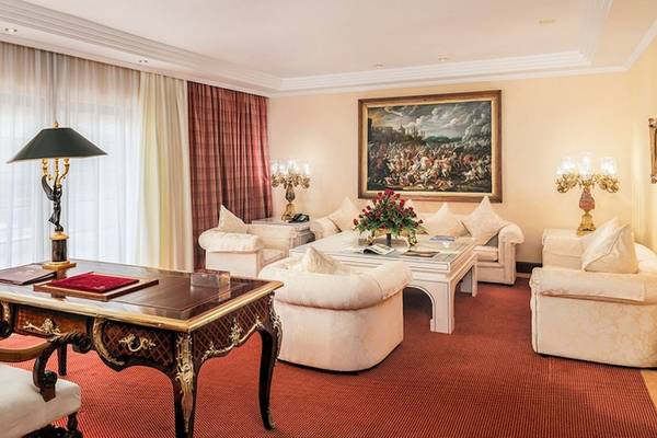 Luxuriöses Hotelzimmer mit einem Arbeitstisch, Sofas, Lampen und einem großen Gemälde an der Wand.