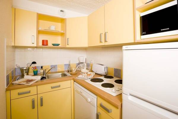 Küche im Belambra Clubs Pineto Hotel mit gelben Schränken und weißen Geräten.