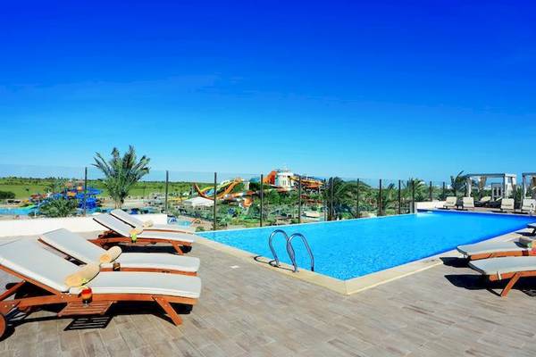 Ein Swimmingpool im Jaz Aquaviva Hotel mit Lounge-Liegen und Wasserrutschen im Hintergrund.