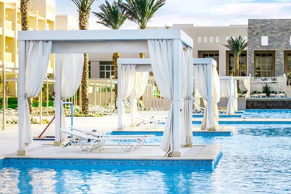 Außenbereich des Jaz Aquaviva Hotels mit Swimmingpools und Liegestühlen unter weißen Vorhängen.