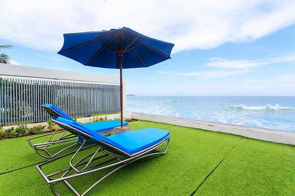 Terrasse mit zwei blauen Liegen und einem blauen Schirm mit Blick auf den Ozean
