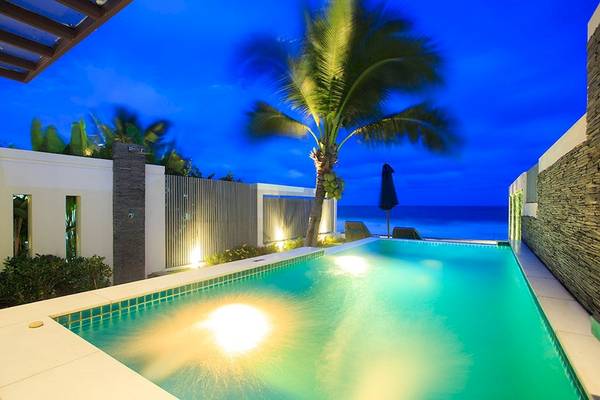 Schwimmbad am Abend mit Palme und Meer im Hintergrund