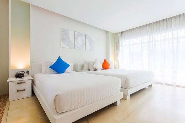 Doppelzimmer im Samui Resotel Beach Resort mit zwei weißen Betten, blauen und orangefarbenen Kissen und weißem Dekor.