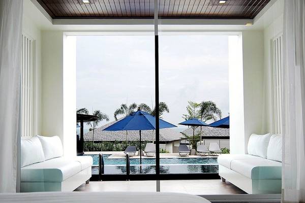 Innenansicht eines Hotels mit Blick auf den Pool und Liegen unter blauen Sonnenschirmen.