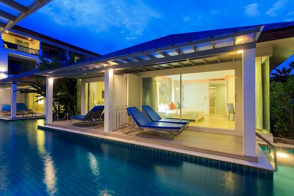 Nachtansicht einer Villa am Samui Resotel Beach Resort mit Swimmingpool und Liegen.