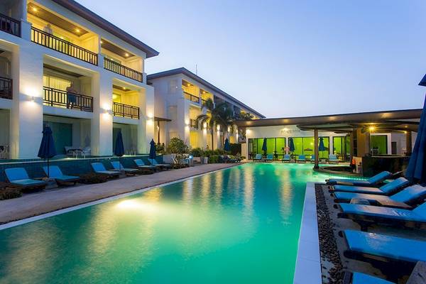 Nachtansicht des Poolbereichs des Samui Resotel Beach Resorts mit blauen Sonnenliegen und beleuchteten Gebäuden.