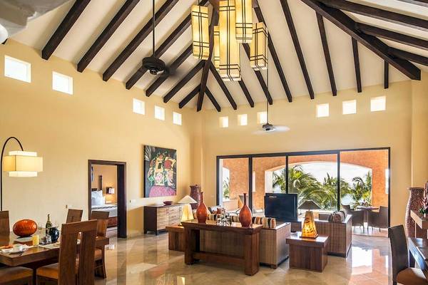 Das Wohnzimmer des Barcelo Maya Palace mit hohen Decken, Holzmöbeln und einem Panoramafenster.