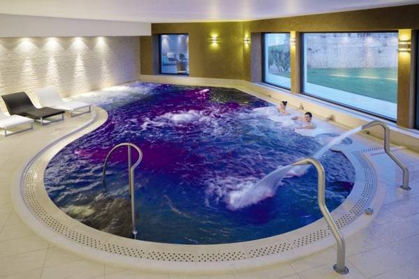 Schwimmbad im MIRA Acaya Golf Resort & SPA mit zwei Personen und Lounge-Sesseln