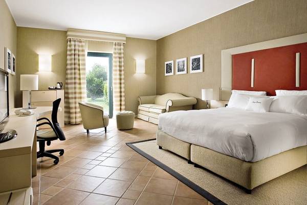 Hotelzimmer im MIRA Acaya Golf Resort & SPA mit großem Bett, Sofa und Fenstern.