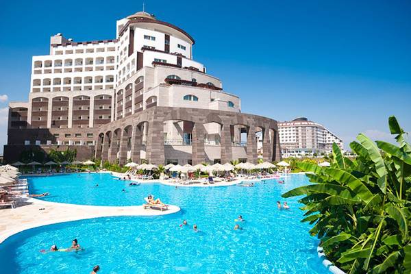 Außenbereich des Melas Lara Hotels mit großem Pool und vielen Gästen.
