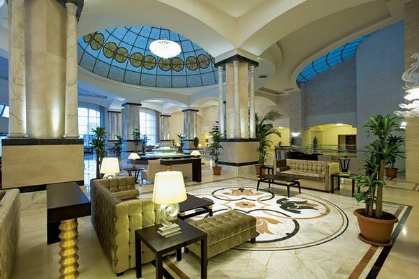 Innenansicht der Hotellobby des Melas Lara mit großen Sofas, Tischen, Lampen und einem großen Teppich.