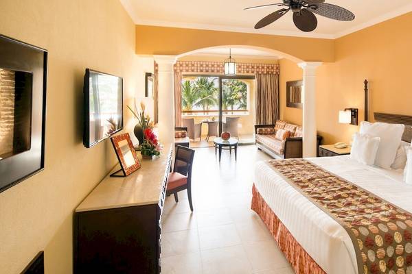 Schlafzimmer im Barcelo Maya Palace Hotel mit großem Bett, Fenstern und Terrassenzugang.
