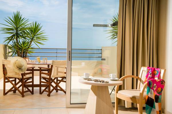 Terrasse mit Meerblick im Blue Marine Resort & Spa mit Tisch, Stühlen und Pflanzen.