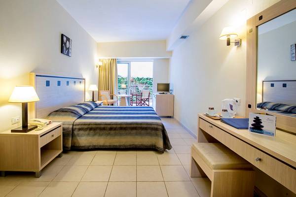 Ein modernes Hotelzimmer im Blue Marine Resort & Spa mit Doppelbett, Schreibtisch und Balkonzugang.