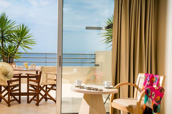 Aussicht auf das Meer vom Hotelzimmer des Blue Marine Resort & Spa mit einem Tisch, Stühlen und einem offenen Balkon.