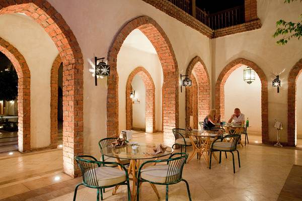 Innenhof des Grand Hotel Sharm El Sheikh mit Bogengängen und Tischen, an denen Gäste sitzen.