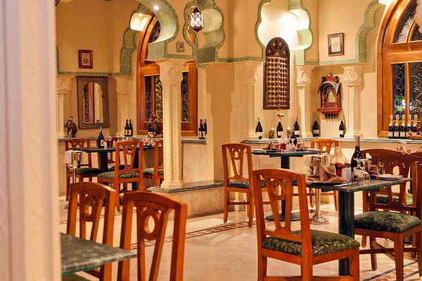 Innenbereich des Grand Hotel Sharm El Sheikh mit eleganten Esstischen und Stühlen, Flaschen und Dekorationen an der Wand.