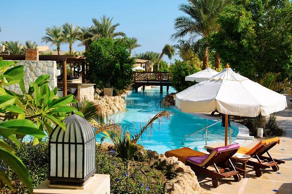 Außenpoolbereich des Grand Hotel Sharm El Sheikh mit Loungestühlen und Sonnenschirmen.