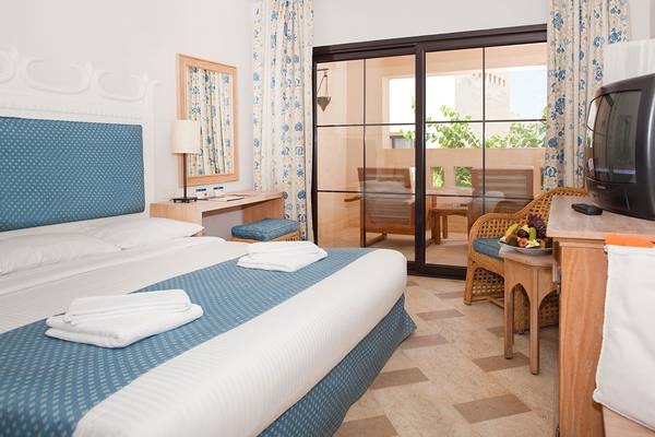 Innenansicht eines Schlafzimmers im Grand Hotel Sharm El Sheikh mit Bett, Tisch, Fernseher und Balkon.