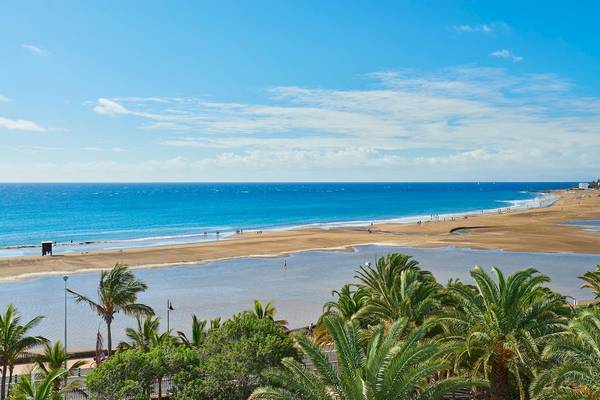 Aussicht auf den Strand von Hipotels La Geria mit blauem Himmel und einigen Menschen am Strand.