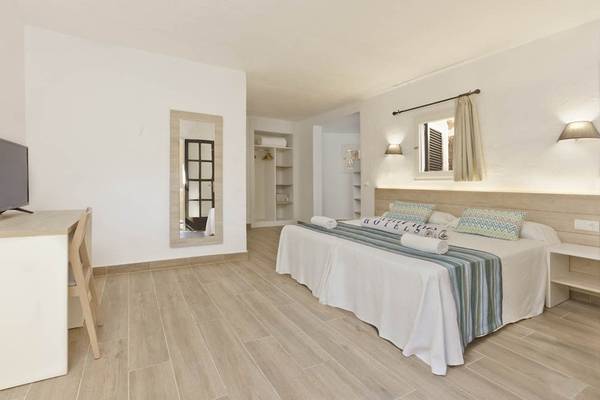 Innenansicht eines Zimmers im Cala Martina by Llum Hotel mit einem Bett, Schreibtisch, Fernseher und Spiegel.