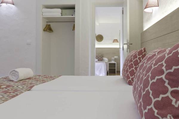 Schlafzimmer im Cala Martina by Llum Hotel mit zwei Betten, weißen Laken und roten Kissen.