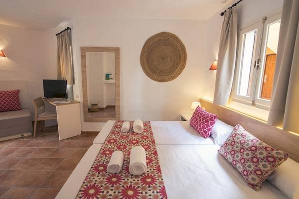 Innenansicht eines Zimmers im Cala Martina Hotel mit zwei Betten, Fernseher, Schreibtisch und Möbeln.