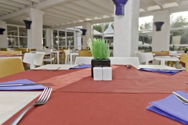 Restauranttisch im Cala Martina by Llum Hotel mit roter Tischdecke, Besteck und Pflanze