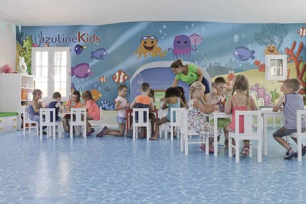 Kinder sitzen in einem blauen Raum mit Meereslebewesen an der Wand.
